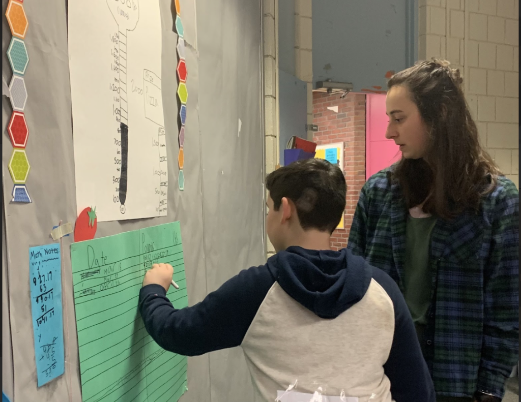 Women helping fifth grader record information about food waste reduction